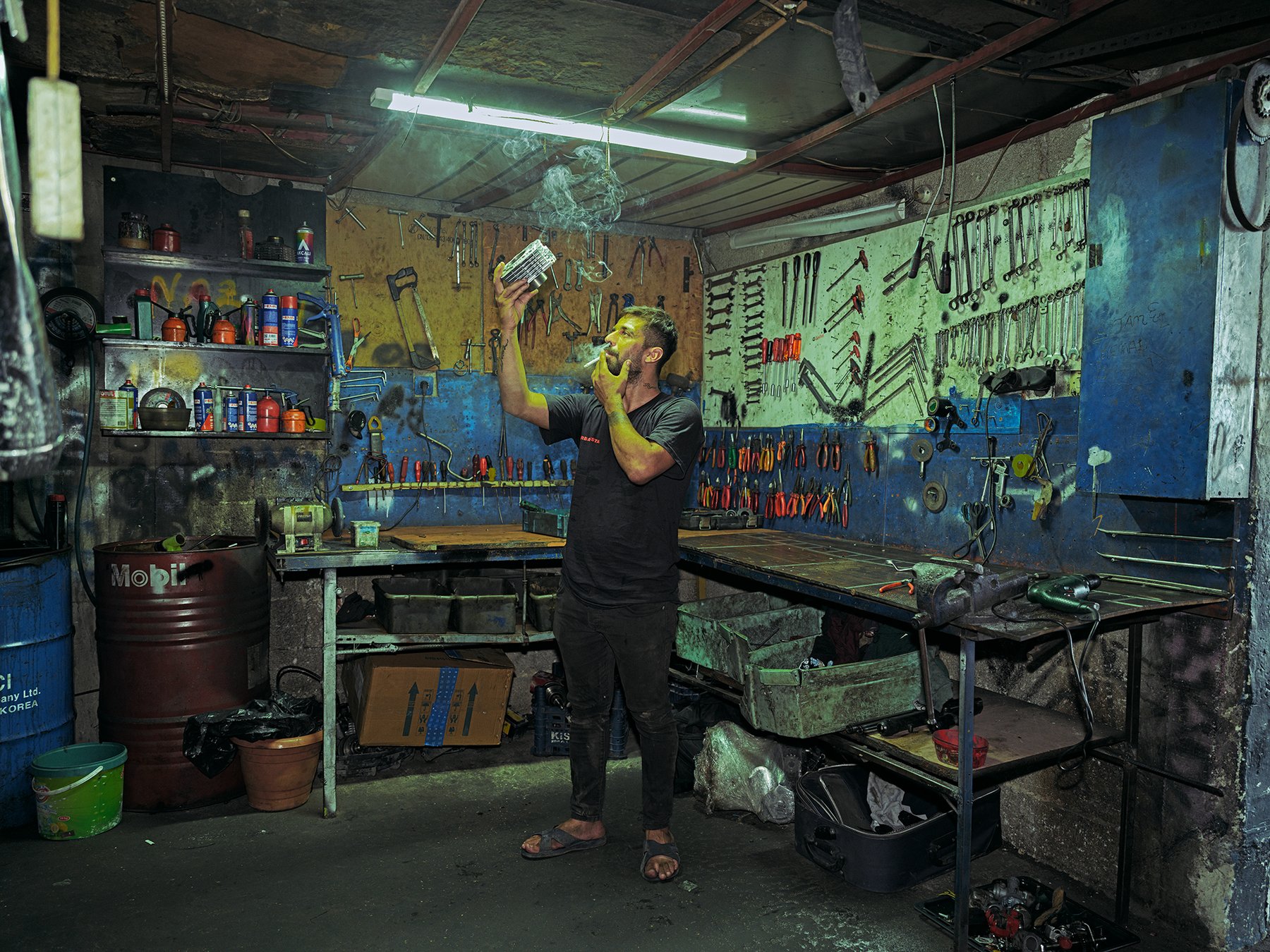 On Two Wheels — a mechanic lighting a cigarette in a workshop
